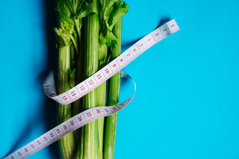 Celery wrapped in a tape measure to prepare for a celery juice detox